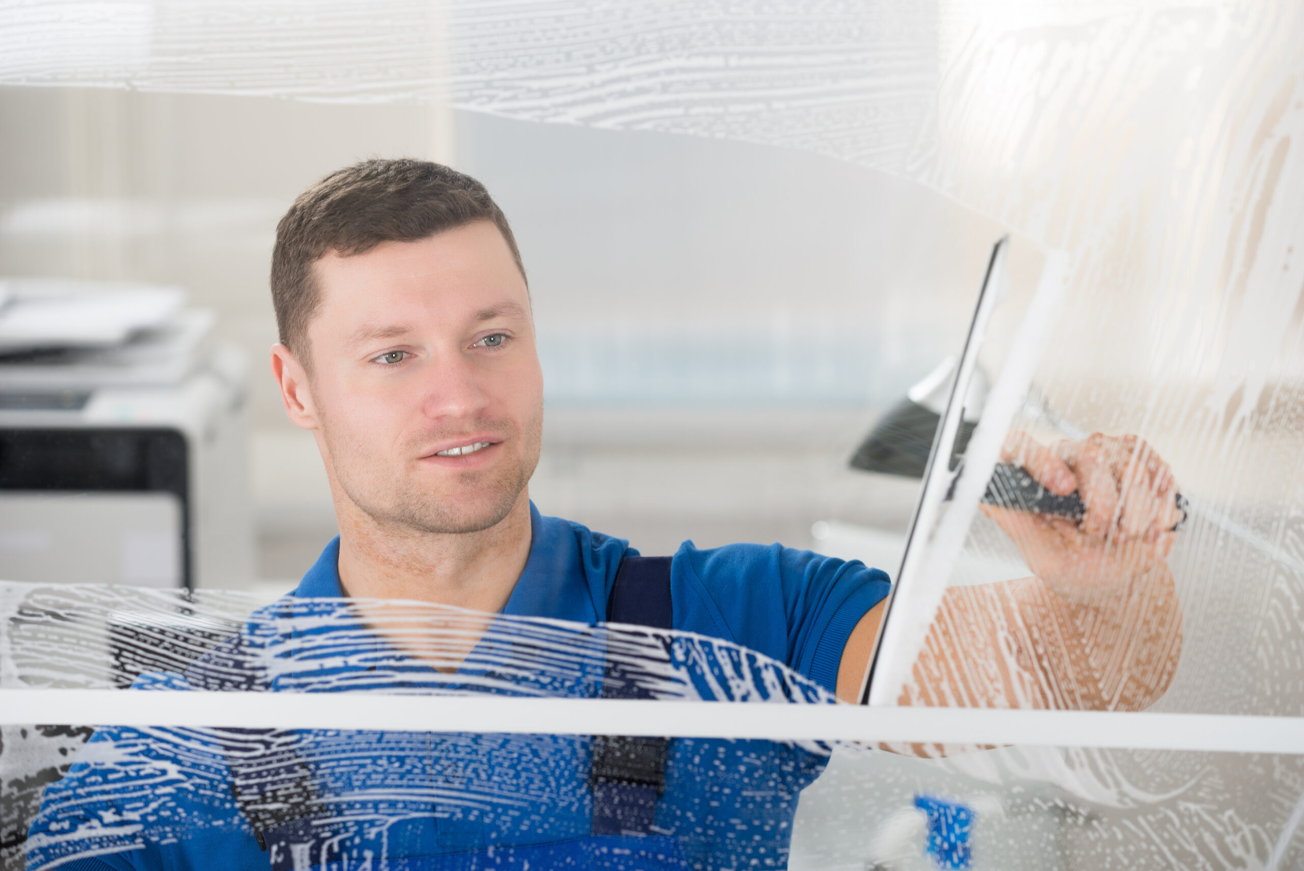Professional worker performing commercial window cleaning on a glass window