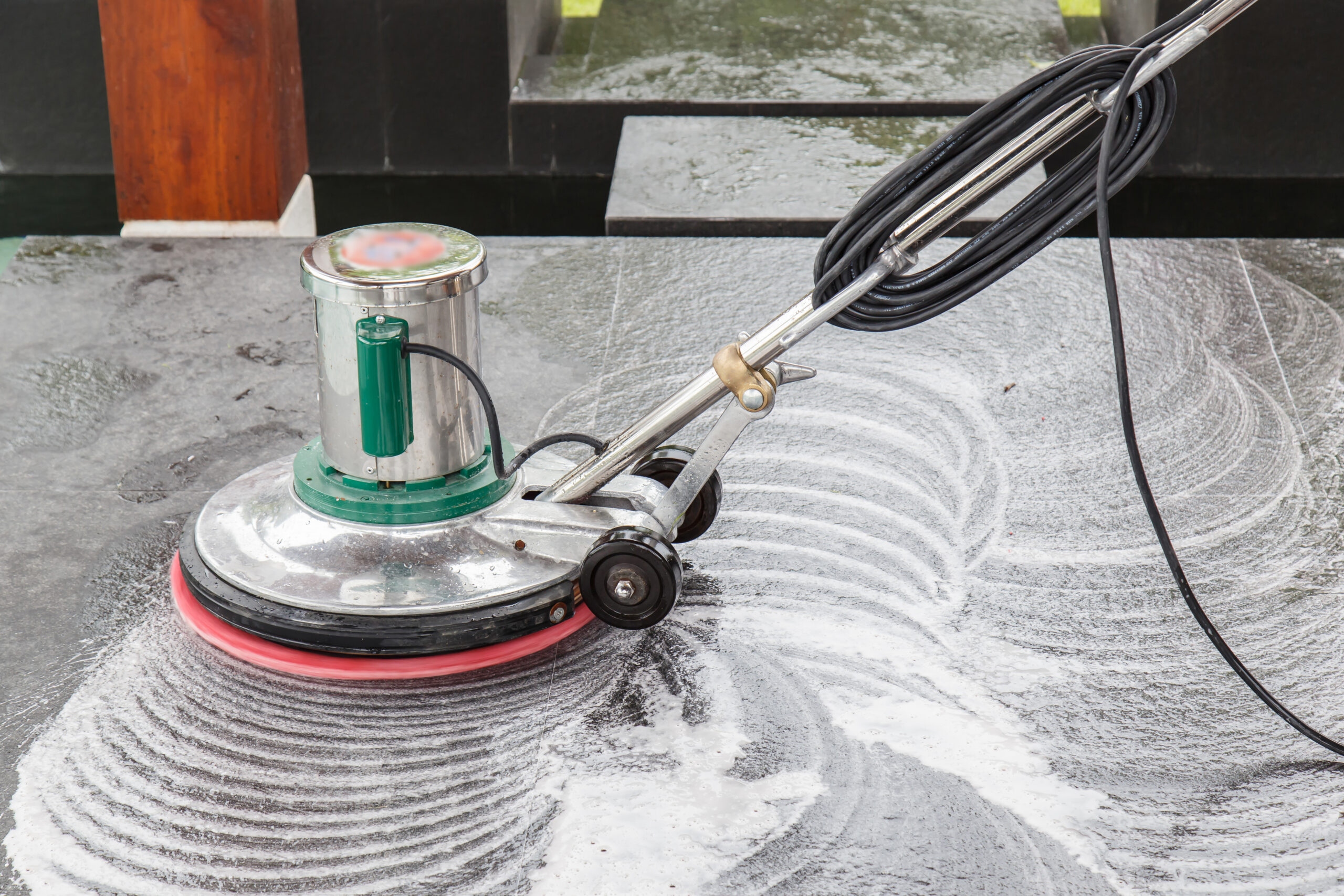 Rotary floor machine stripping and polishing hard retail flooring to restore its protective finish