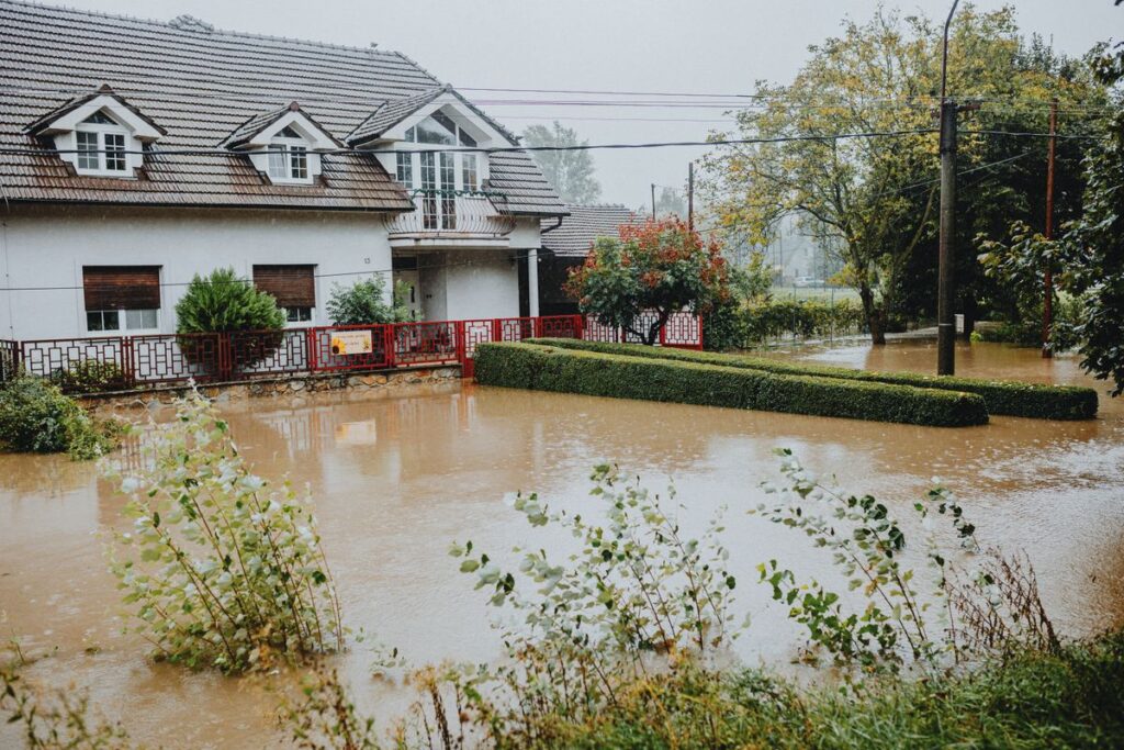 A suburban property surrounded by floodwaters after heavy rain, illustrating water damage risk